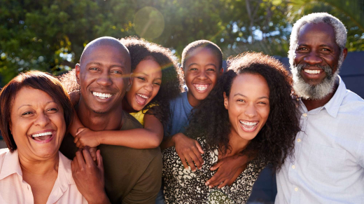 Outdoor Portrait Of Multi-Generation Family In Garden At Home Against Flaring Sun
