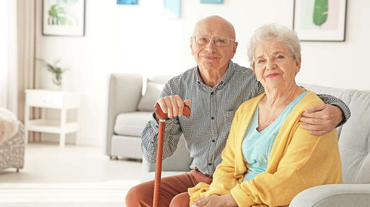 Elderly couple sitting on couch smiling at camera