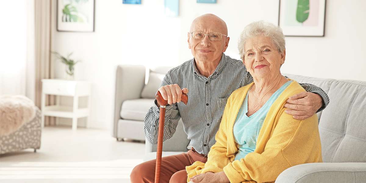 Elderly couple sitting on couch smiling at camera