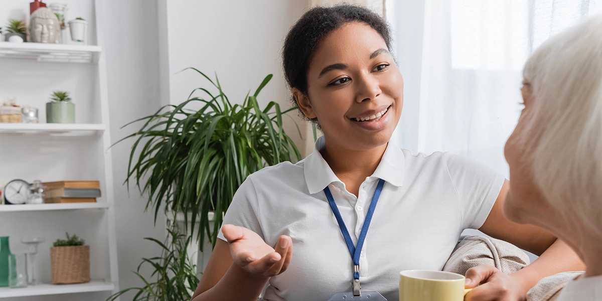 happy multiracial social worker chatting with senior woman