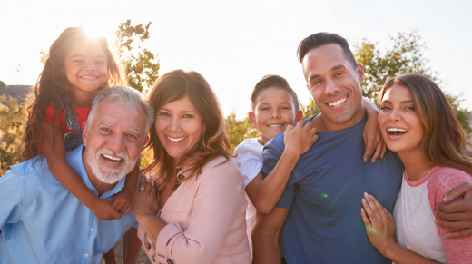 Portrait Of Multi-Generation Hispanic Family Relaxing In Garden At Home Together