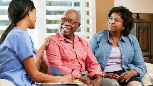 Nurse and senior couple talking at a home visit